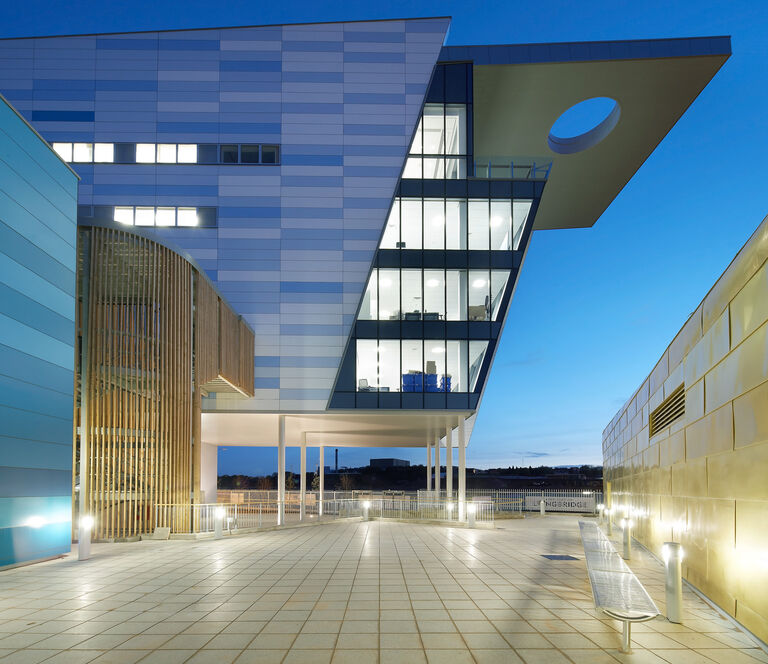 Entrance of new campus building for Bournville College in Birmingham, featuring 10m high glazed wall, Siberian Larch glulam frames and gold metallic sheets.